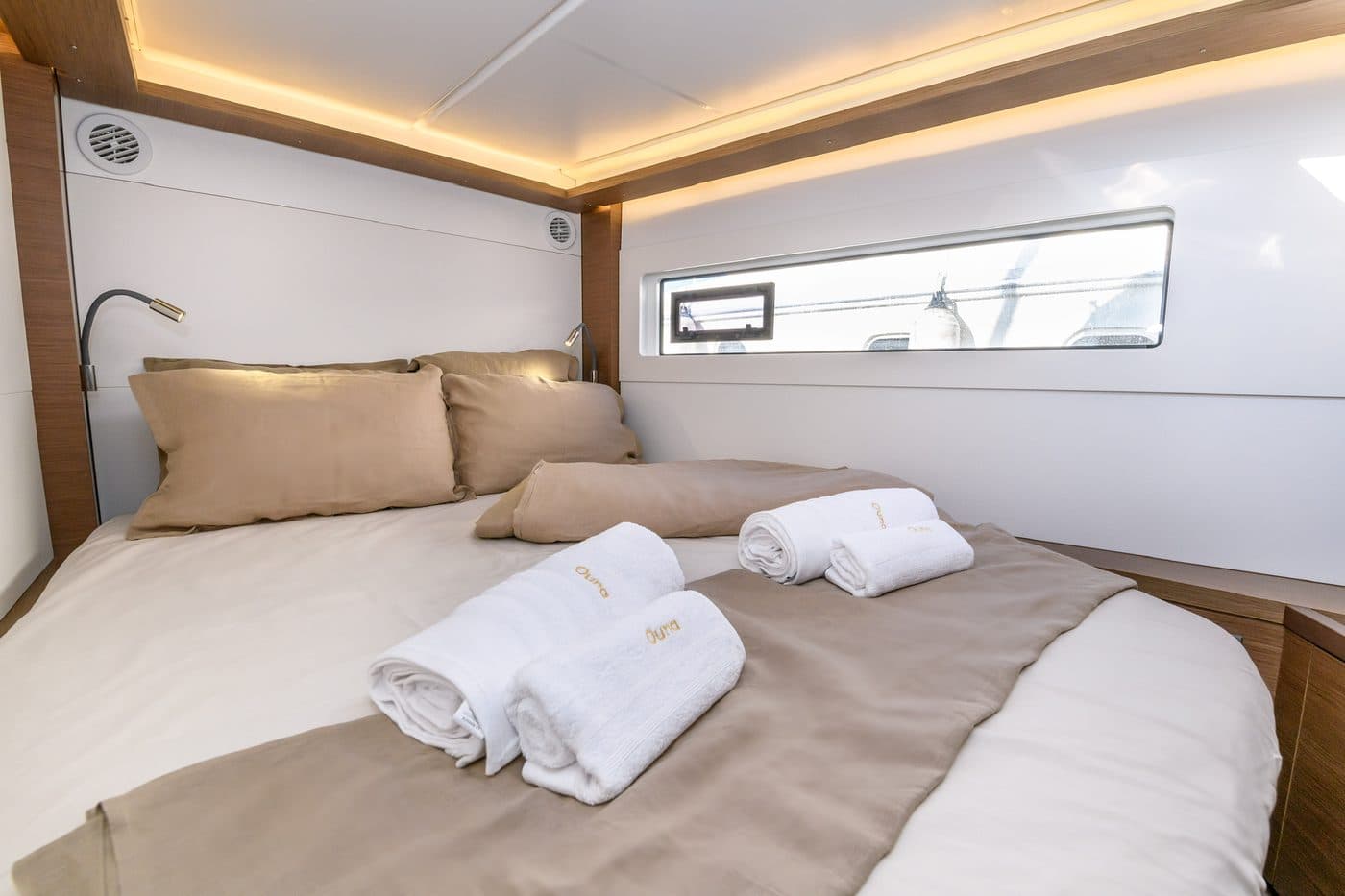 Guest cabin with sand linen, soft ambient lighting, and a marina view through a long window