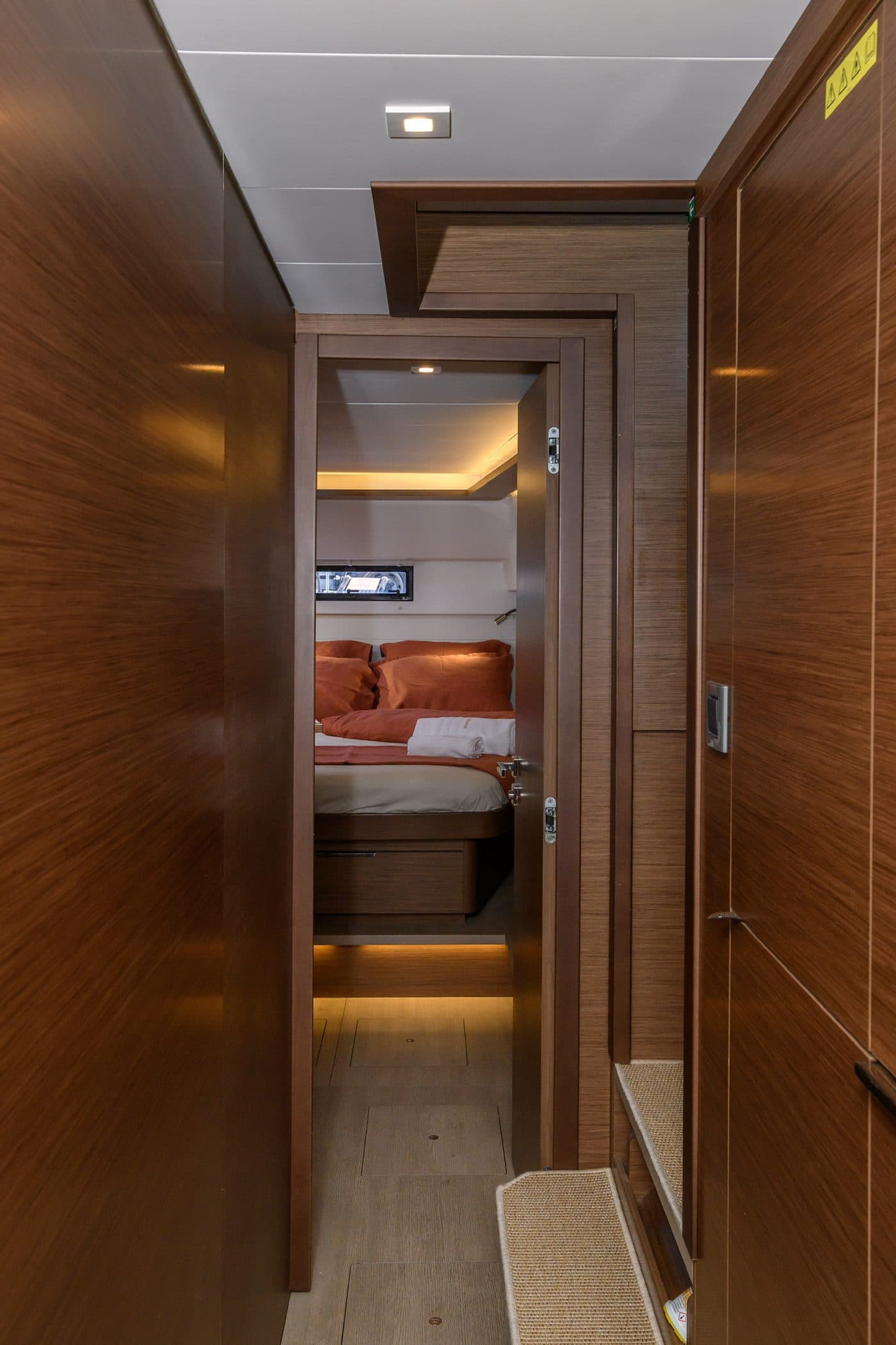 Wood-panelled corridor opening into a coral-linen cabin