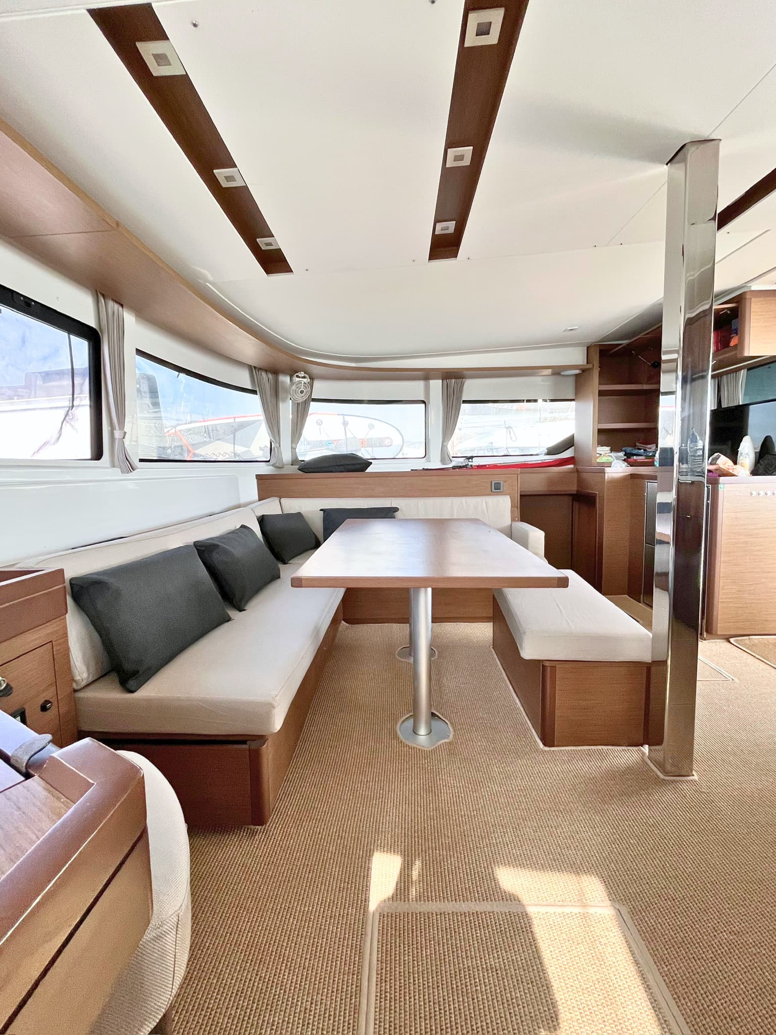 The saloon settee and dining table, with the galley beyond and sun across the sole