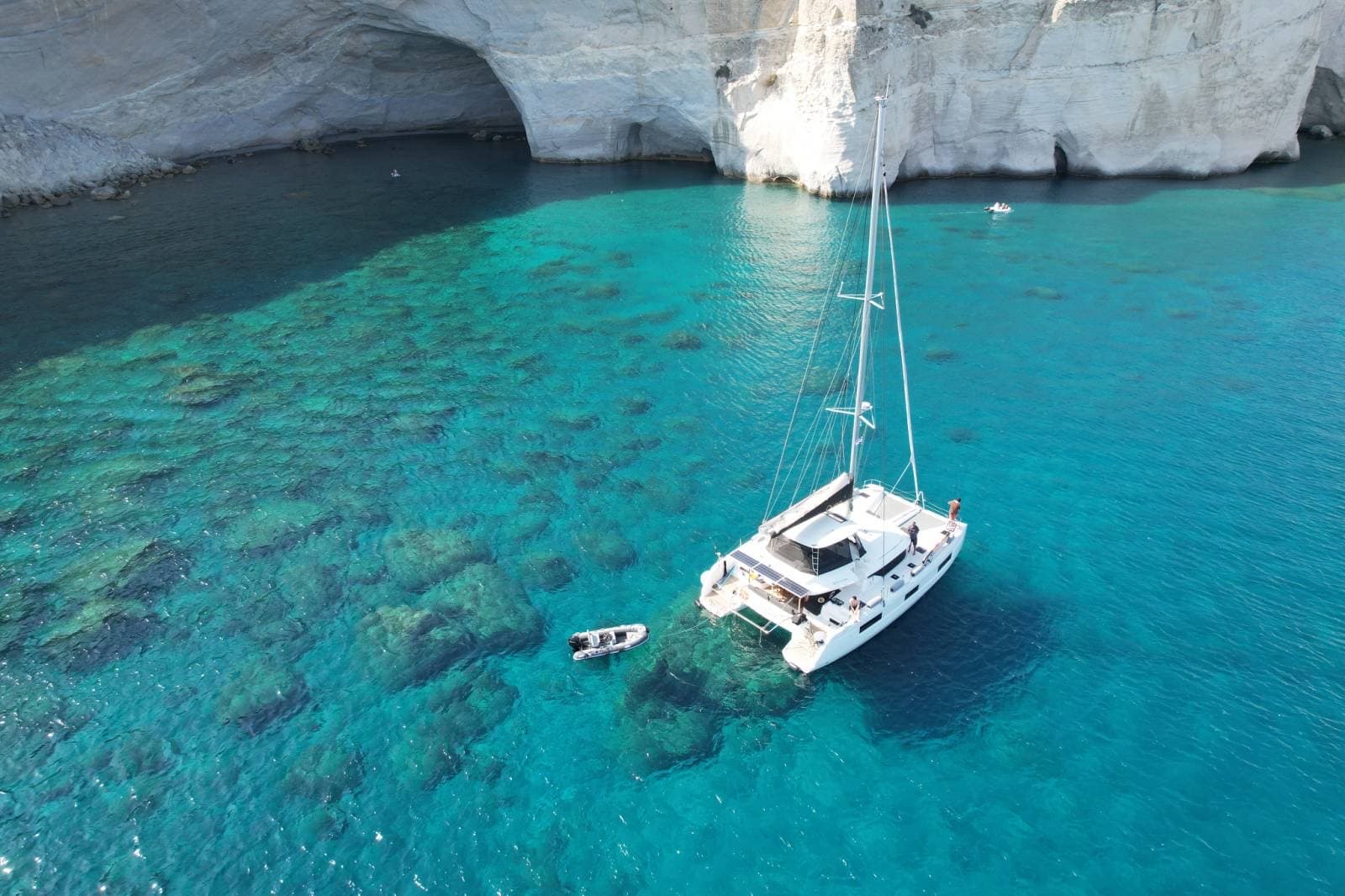 Ouna catamaran anchored in a Cycladic cove with turquoise water